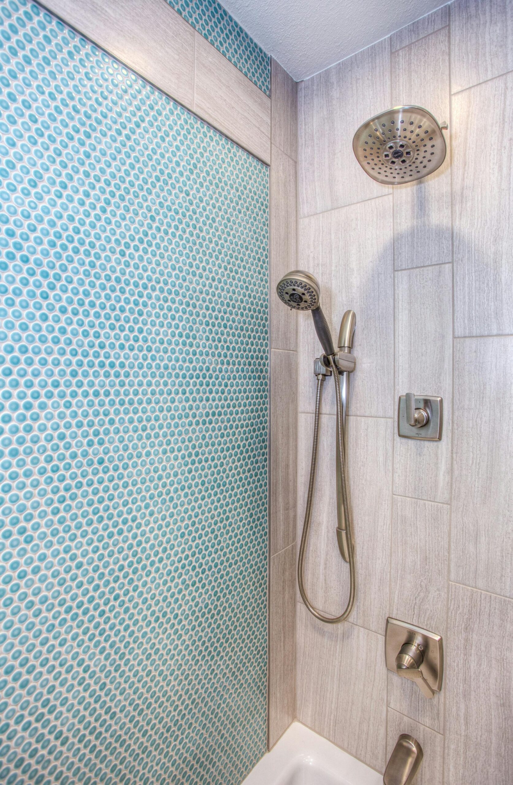 Elegant shower design featuring blue mosaic tiles and stainless steel fixtures.